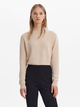 A lady wears a beige sweater.